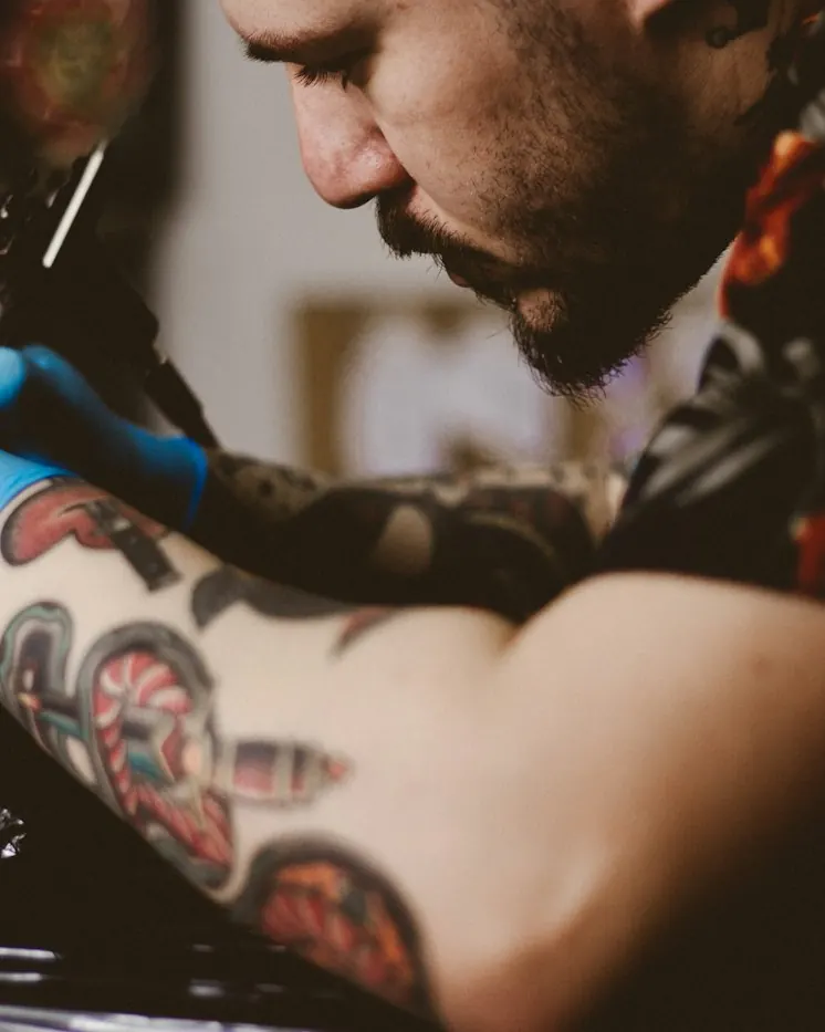 An artist tattooing a client's arm